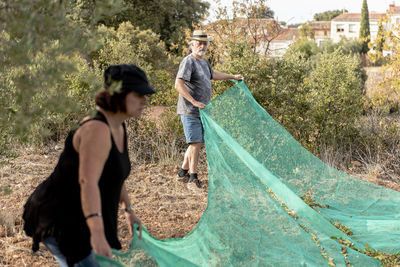 Male and female farmers harvesting almonds by hand.