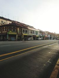 Road by buildings against clear sky