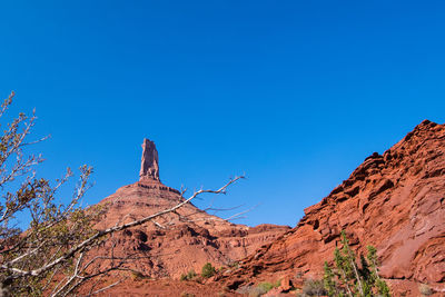 Low angle view of rocky mountain against clear blue sky