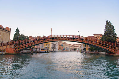 Bridge over river in city against clear sky