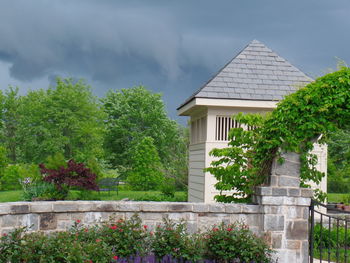 House and trees by building against sky
