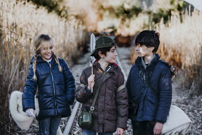 Group of three children hiking in the woods walking in a train track