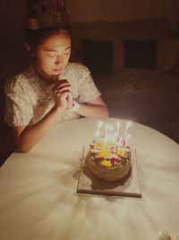 Girl blowing birthday cake on table