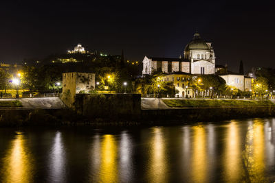 Illuminated buildings by river at night