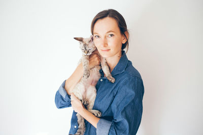 Portrait of woman holding cat against white background