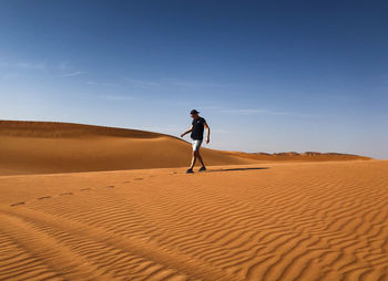 Full length of man on sand dune in desert against sky