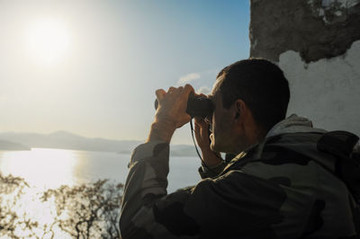 Portrait of man photographing against sky