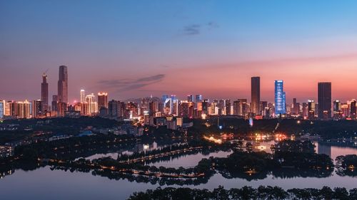 Illuminated cityscape by lake at night