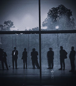 Rear view of silhouette people standing against window