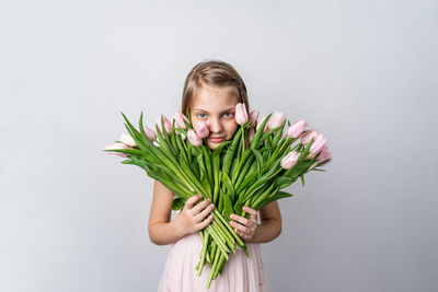 Portrait of smiling girl holding plant against white background