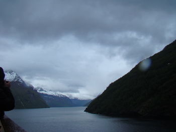 Scenic view of river by mountains against sky
