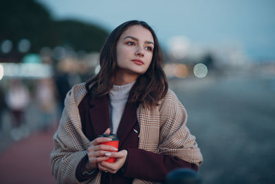 Portrait of beautiful woman standing against blurred background