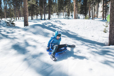 High angle view of girl in sledge sliding at snow covered field