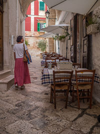 Rear view of woman standing on chair against buildings in  locorotondo, italy.