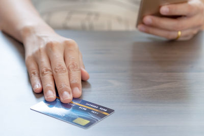 Close-up of hands holding smart phone on table