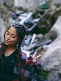 Young woman puckering lips while standing against mountain