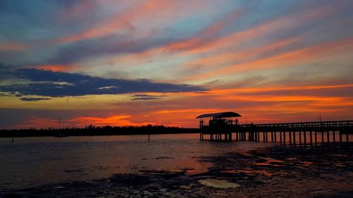 Silhouette pier on beach against sky during sunset
