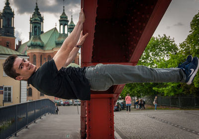 Smiling young man in city against sky