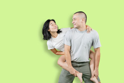 Young couple standing against green background