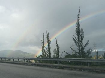 Rainbow over road against sky