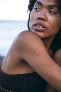 Black multiracial woman lifestyle portrait by the ocean in a swimsuit