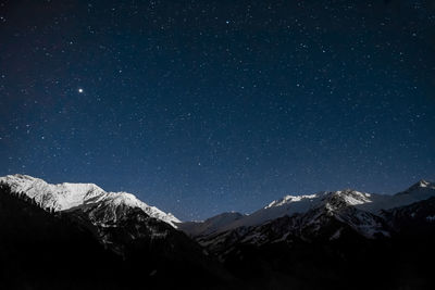 Scenic view of snowcapped mountains against sky at night