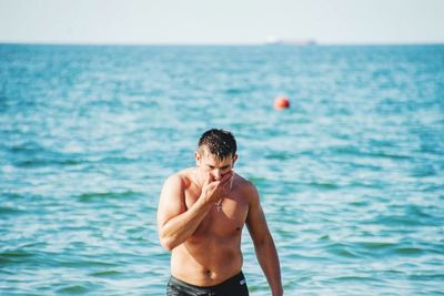 Shirtless man standing in sea against sky