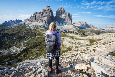 Rear view of woman walking on rock against sky