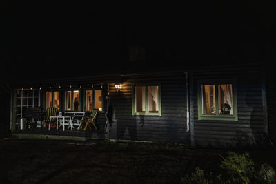 Shadow of demon on illuminated cabin at night