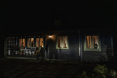 Shadow of demon on illuminated cabin at night