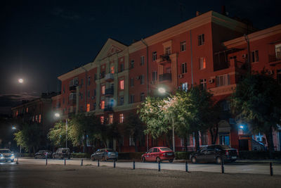 Illuminated building by street at night