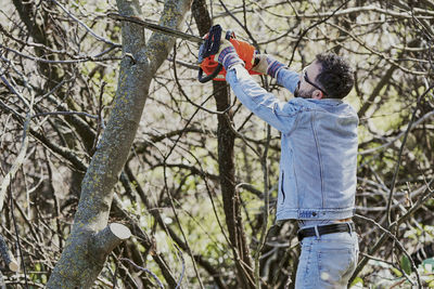 Man standing by bare tree in forest