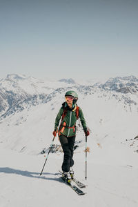 Man skiing on snowcapped mountain against clear sky