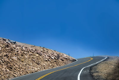 Surface level of empty road against blue sky