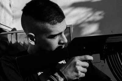 Close-up of young man aiming with rifle