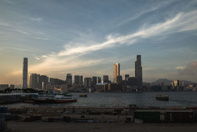Sea by modern buildings against sky in city