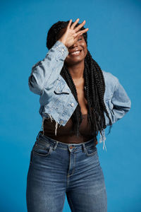 Young woman standing against blue background