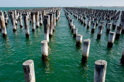 Wooden posts on pier over sea against sky