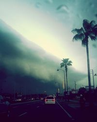 Cars on road against cloudy sky