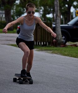 Full length of woman riding longboard on road