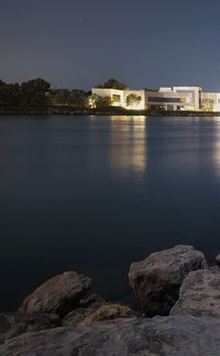 River by illuminated buildings against sky at night