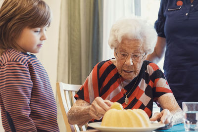 Boy and great grandmother looking at sponge cake in house