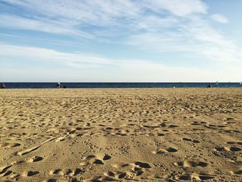 Close-up of footprints on beach against sky