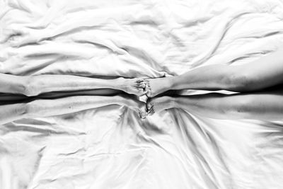 Low section of women with barefoot lying on bed at home