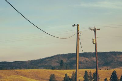 Electricity pylon on field against sky