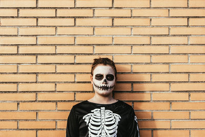 Portrait of young man standing against brick wall