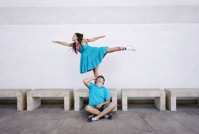 Full length of young woman sitting on wall