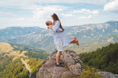 Man carrying woman while standing on mountain