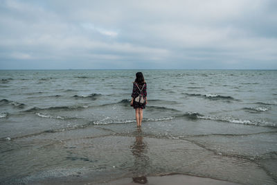 Woman standing on beach against sky