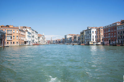 Buildings by sea against clear blue sky